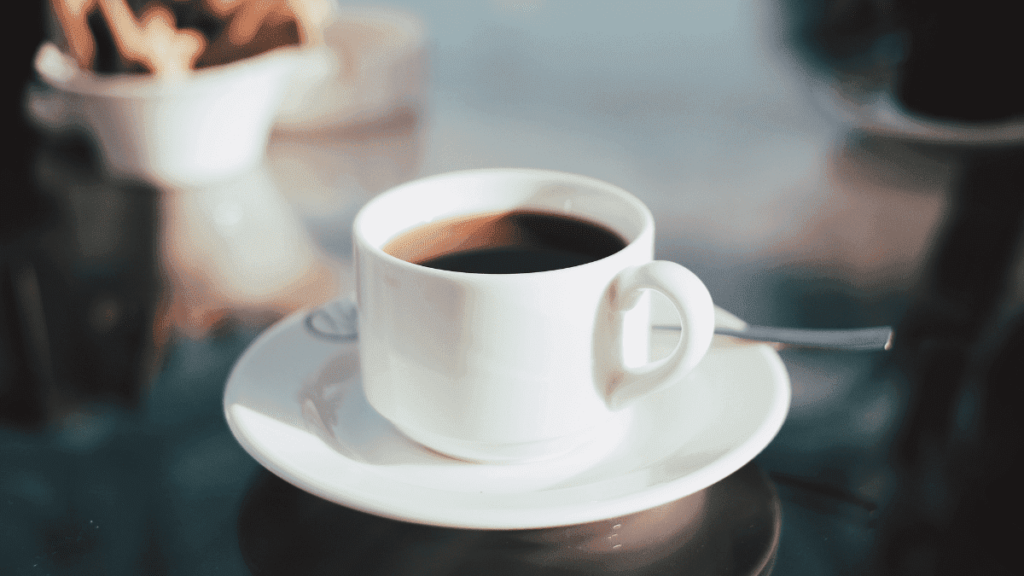 Xicara de café sobre o pires com colher de chá em cima da mesa.