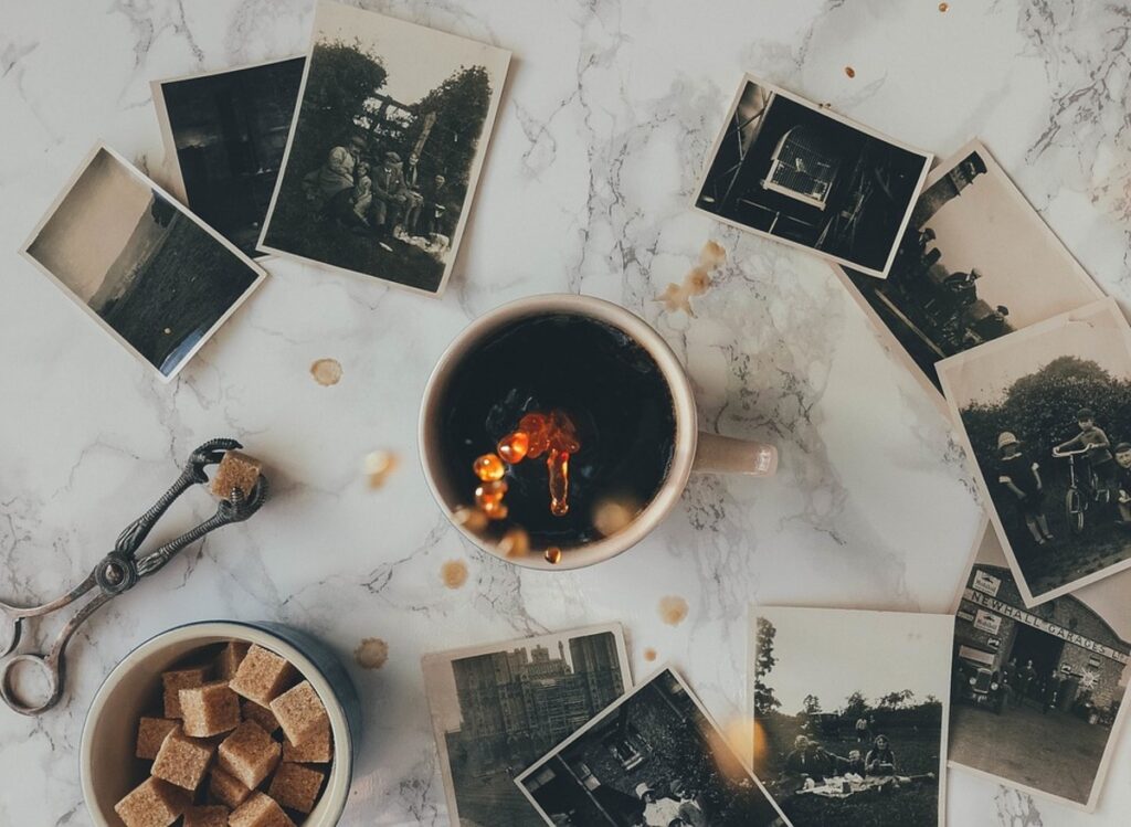 Mesa de mármore com xícara de café, algumas fotos antigas e cubos de açúcar em um bowl