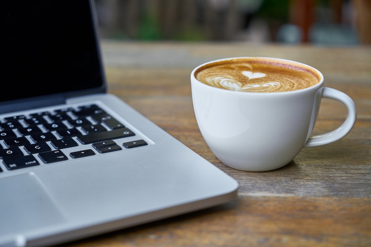 xícara de café do lado de um notebook