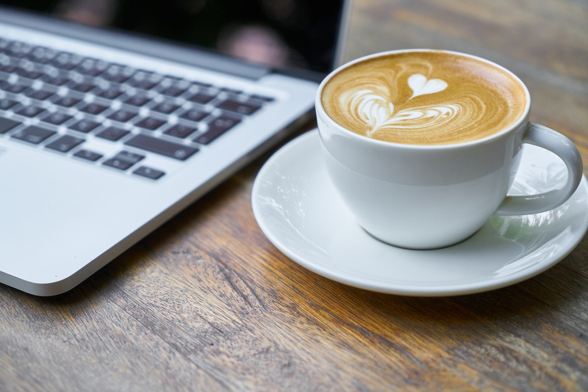 xícara de café do lado de um laptop