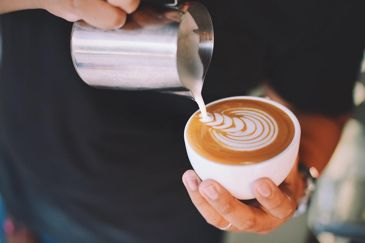 Barista colocando leite em cafpe espresso fazendo Café complexo