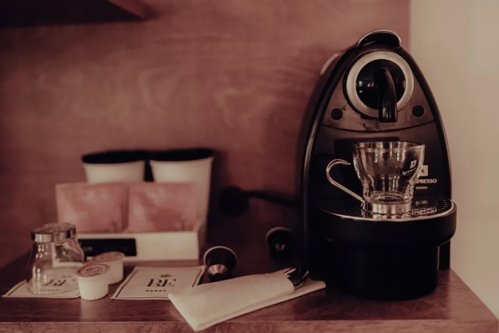 Máquina de café expresso, xícara de vidro e acessórios em um cantinho do café.