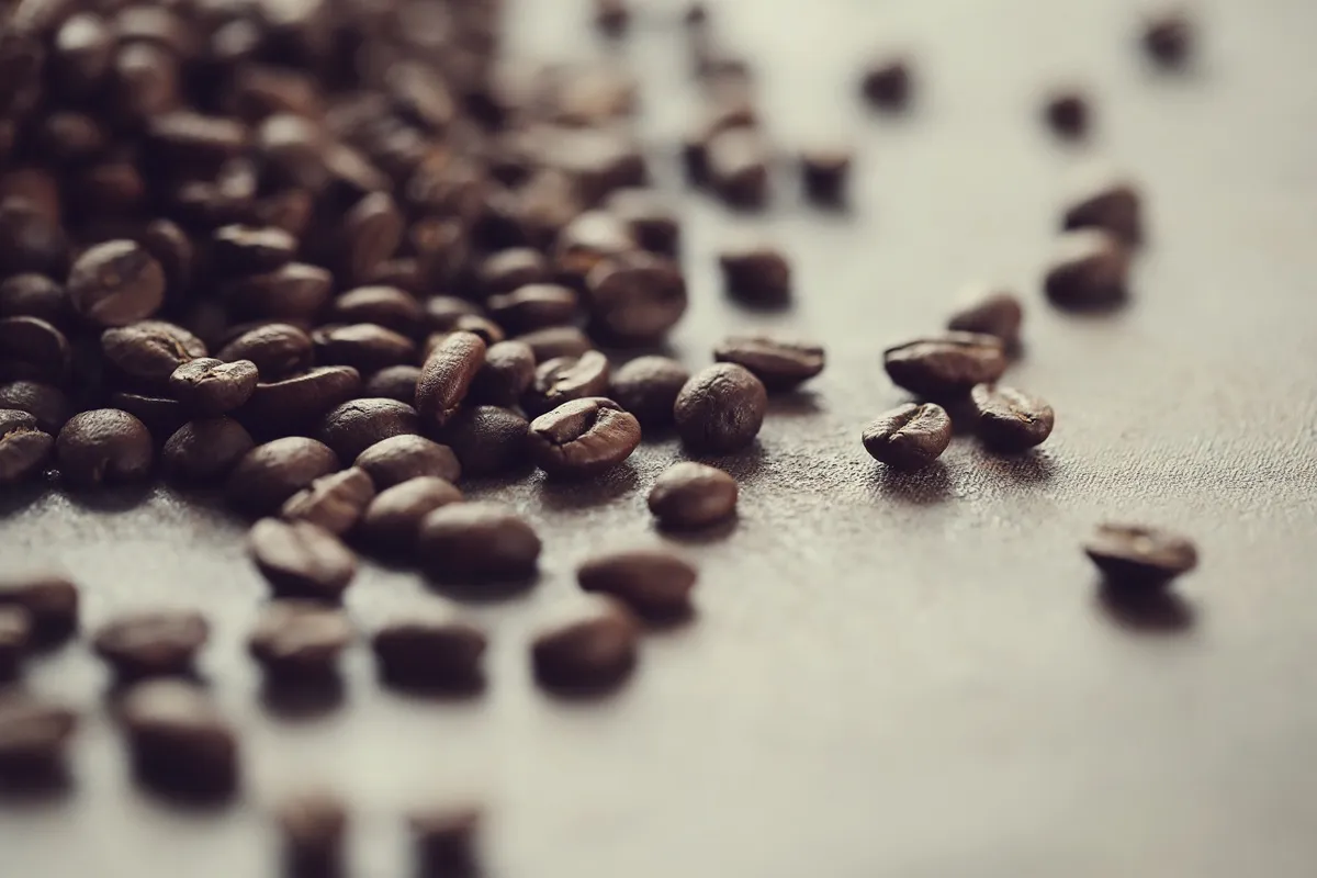 Grãos de café torrados espalhados sobre uma superfície lisa em close-up.