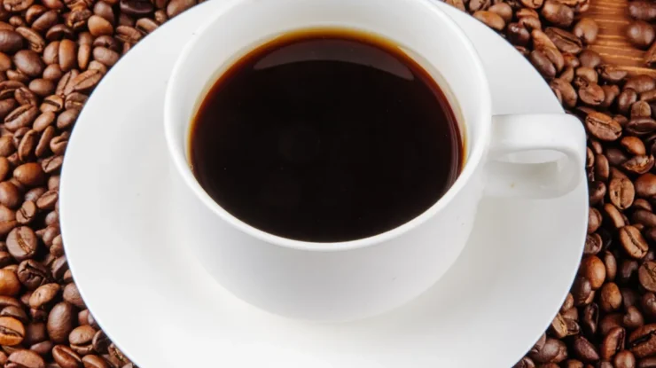 Grãos de café robusta torrados em close, com brilho natural e fundo escuro.