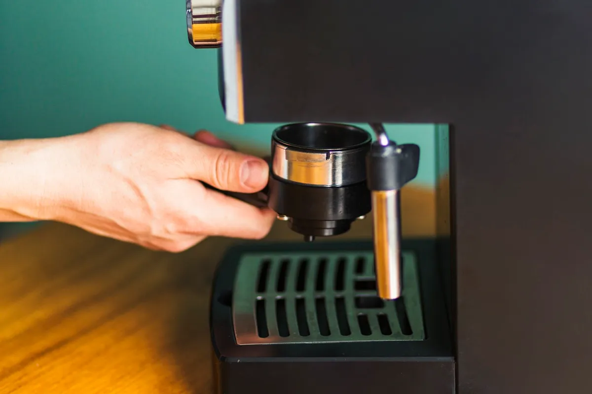 Barista colocando o portafiltro na máquina de espresso para preparar café, destacando a ação de fazer café de alta qualidade