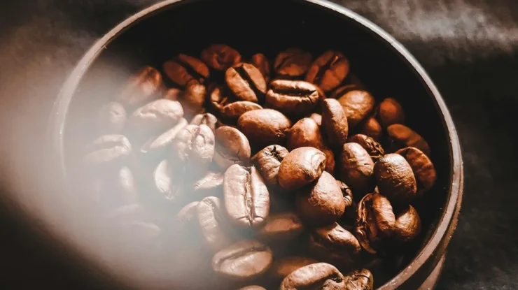 Imagem de grãos de café frescos dentro de um recipiente, com foco em sua textura e tonalidade, representando a qualidade do café em grão.