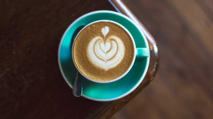 cappuccino diet, arte de latte de coração em xícara turquesa em mesa de madeira escura.