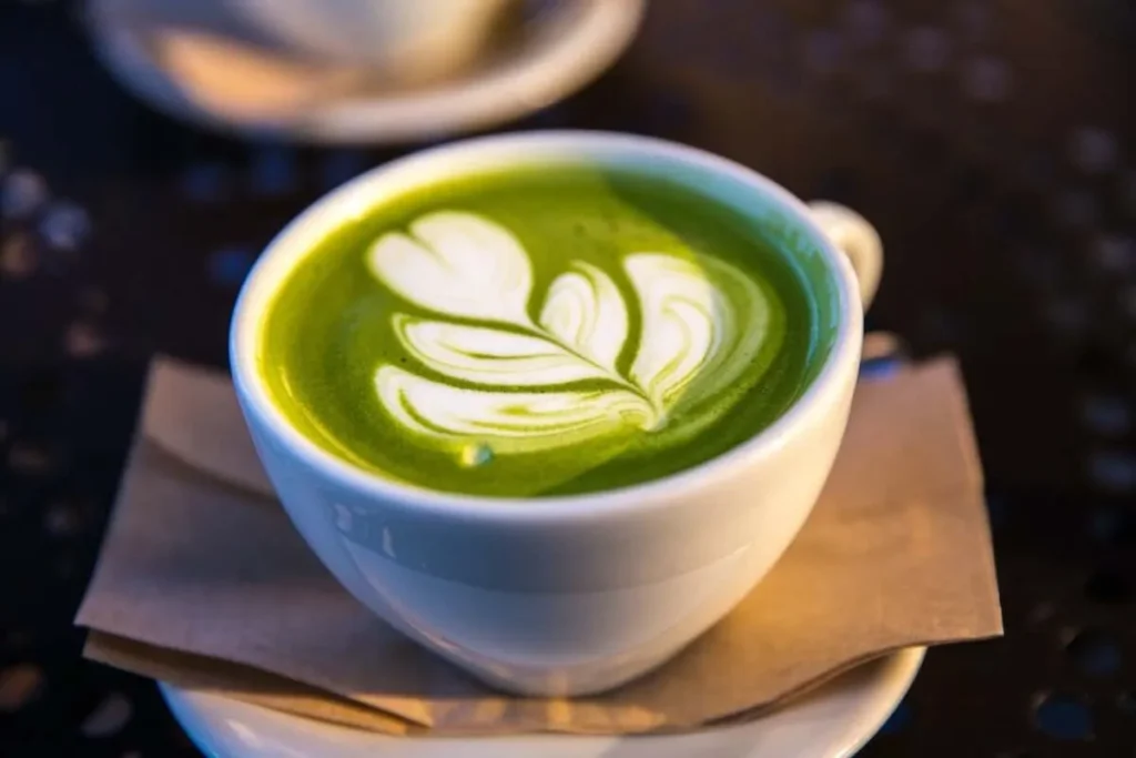 Xícara de matcha latte verde vibrante com arte em forma de folhas na espuma.