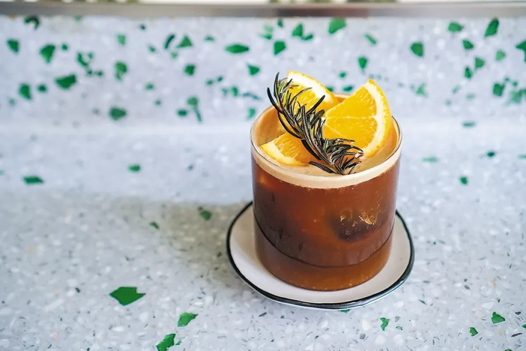 Salão interno do restaurante Coco Bambu de Florianópolis, com mesas de madeira postas, uma parede de tijolos e iluminação aconchegante.